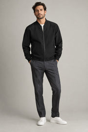 Male model wearing modern bomber jacket in black on a neutral studio background