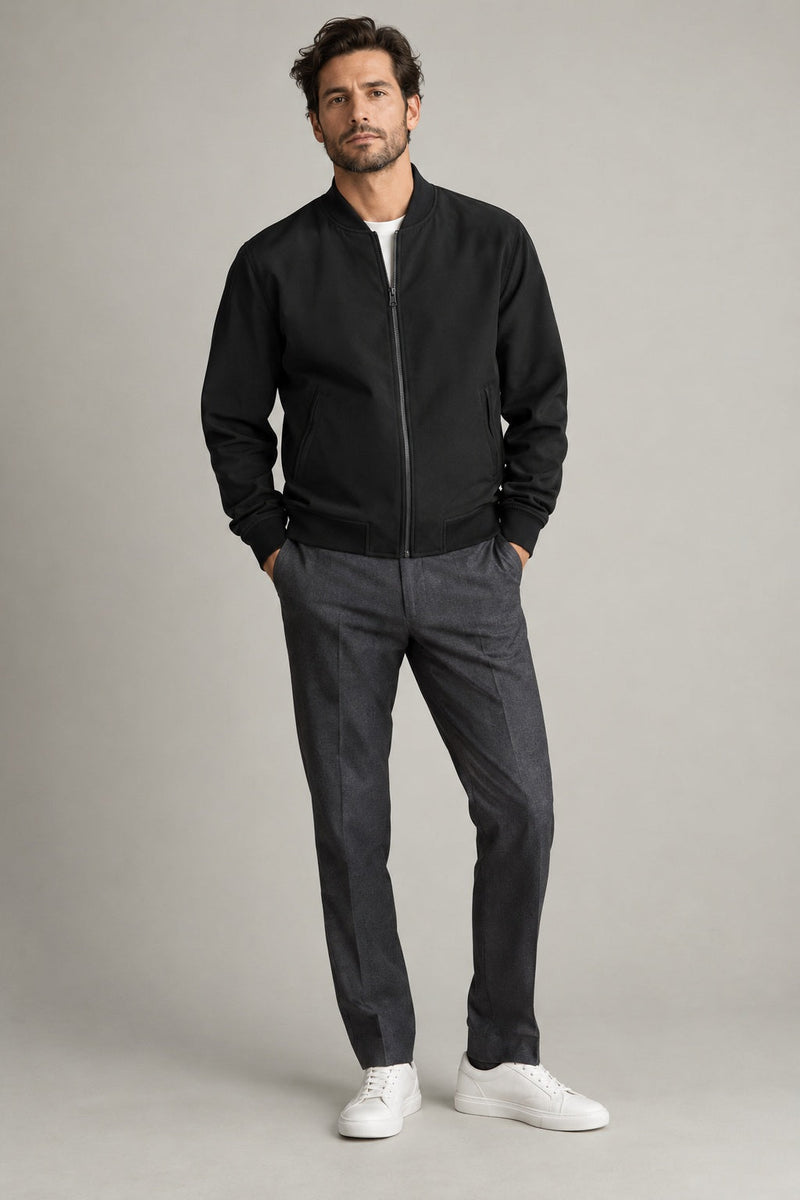 Male model wearing modern bomber jacket in black on a neutral studio background