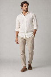 Male model wearing relaxed summer shirt in white on a neutral studio background