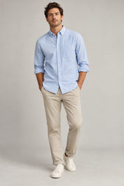Male model wearing relaxed oxford shirt in light blue on a neutral studio background