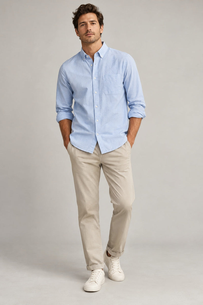 Male model wearing relaxed oxford shirt in light blue on a neutral studio background