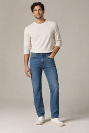 Male model wearing straight-leg denim in blue on a neutral studio background